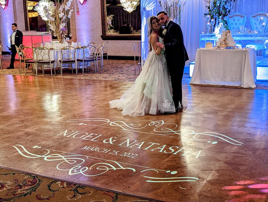 Flourished monogram projected across a wooden dance floor