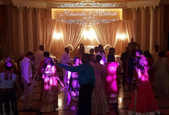 Packed dance floor beneath a projected wedding monogram